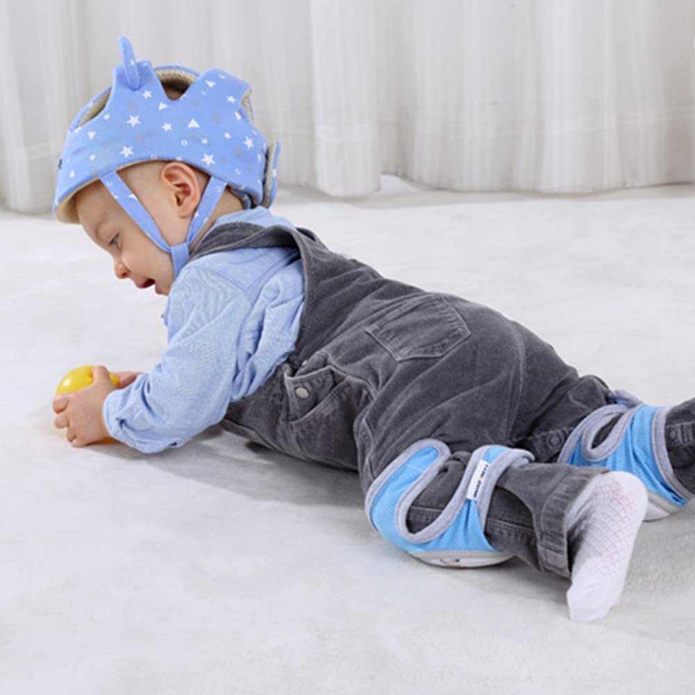Baby wearing a blue helmet and knee pads on a white surface