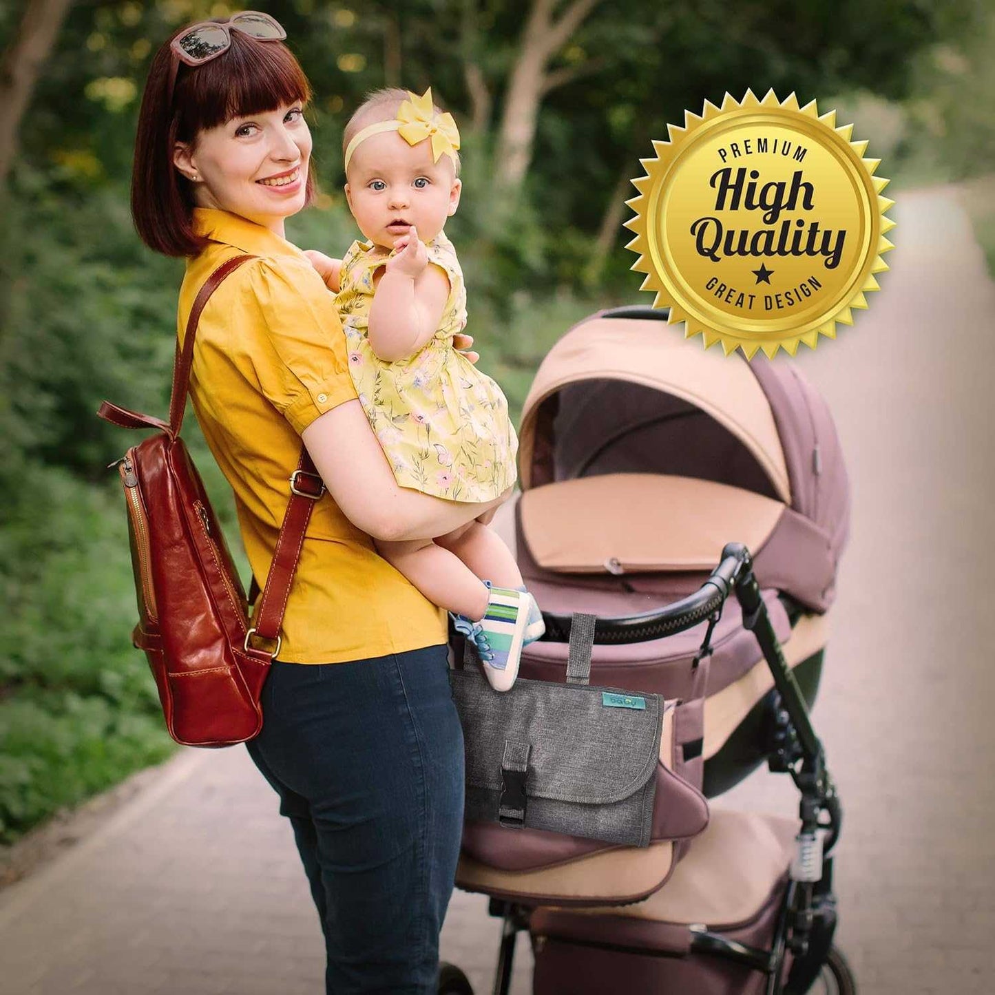 Woman holding a baby with a stroller in the background, outdoors.