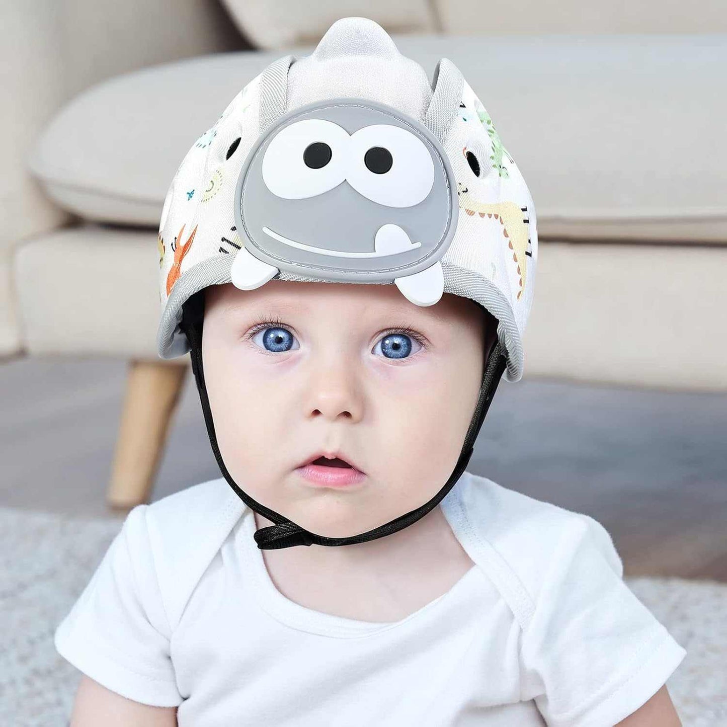 Baby wearing grey dinosaur themed baby safety helmet for toddler protection during crawling and walking