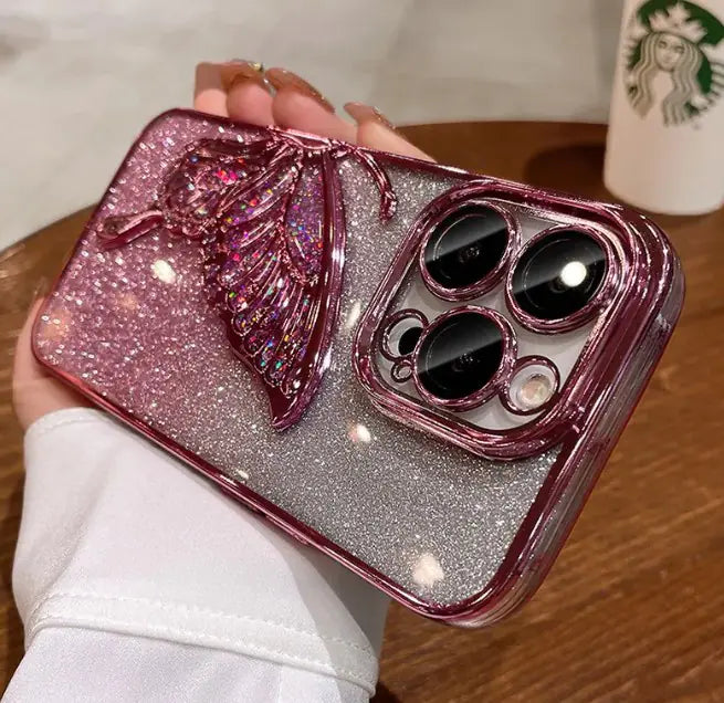 Phone case with pink butterfly design held by a person, Starbucks cup in the background
