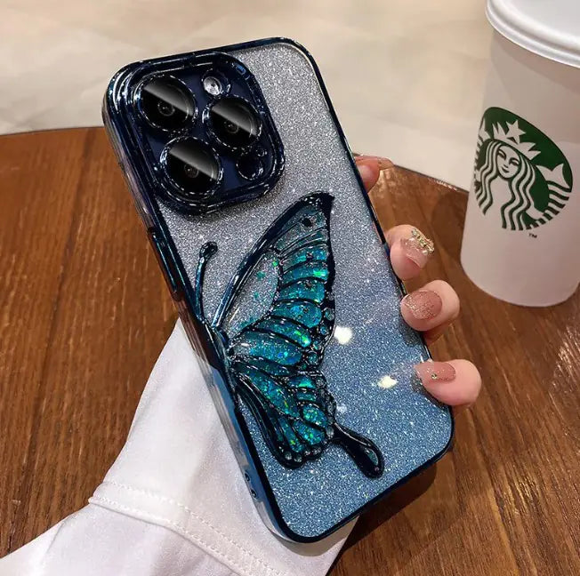 Phone case with butterfly design held by a hand, Starbucks cup in the background
