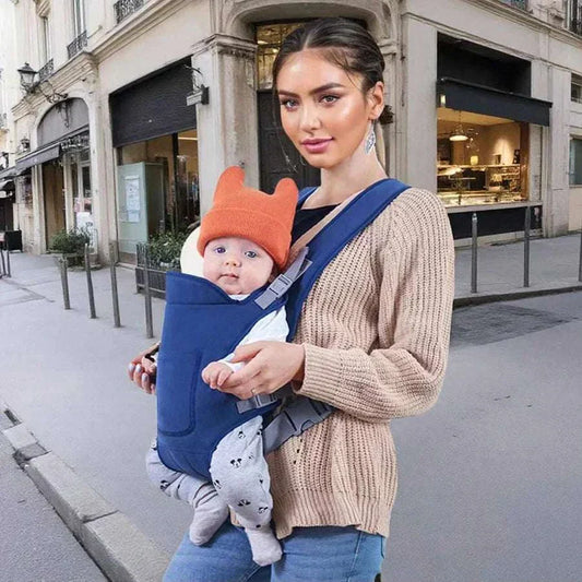 Mother carrying baby in blue infant baby carrier outdoors on city street