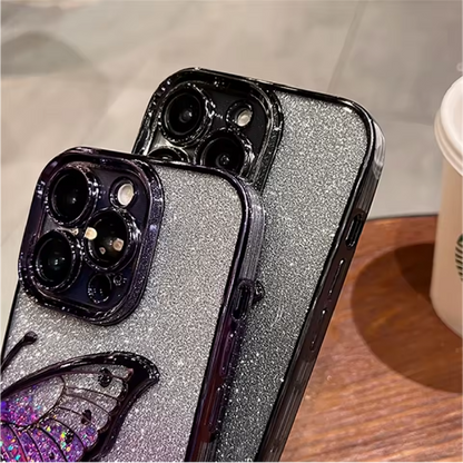 Two phone cases with glittery finish and butterfly design on a wooden surface.