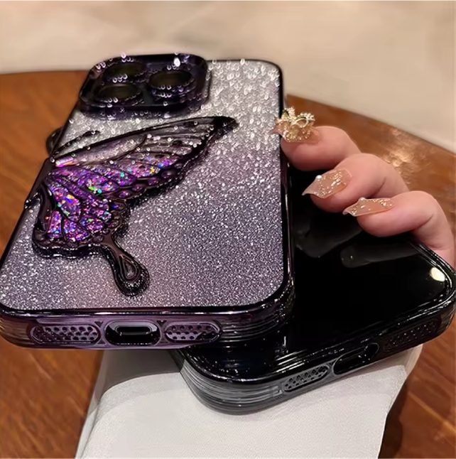 Two phone cases with glittery finish and butterfly design on a wooden surface.