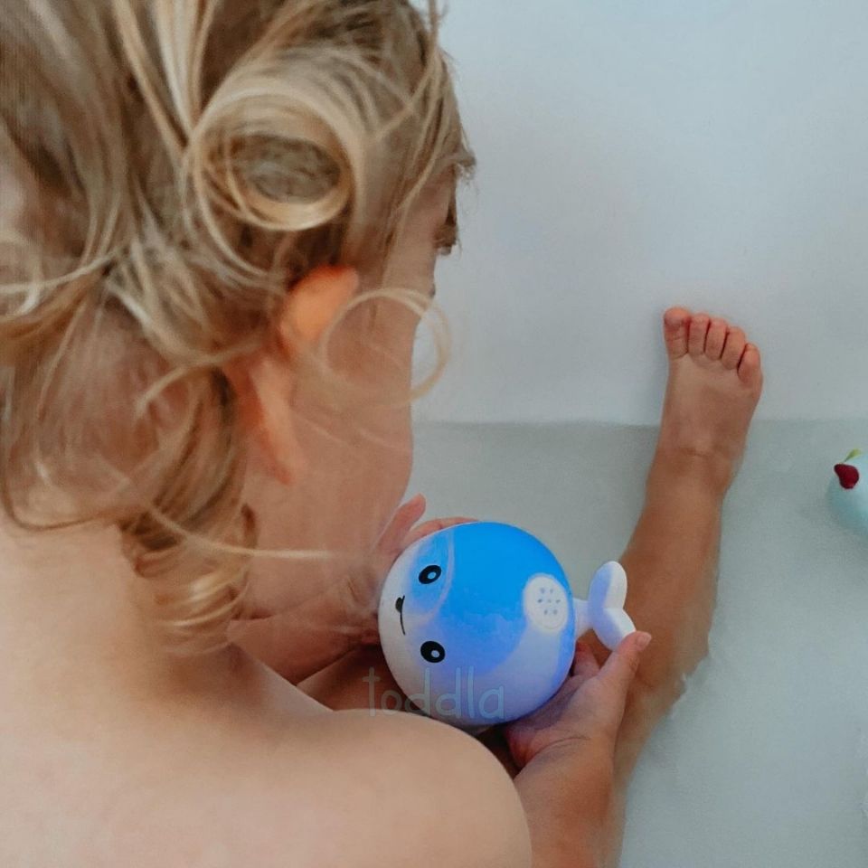 Child playing with a blue toy in a bathtub