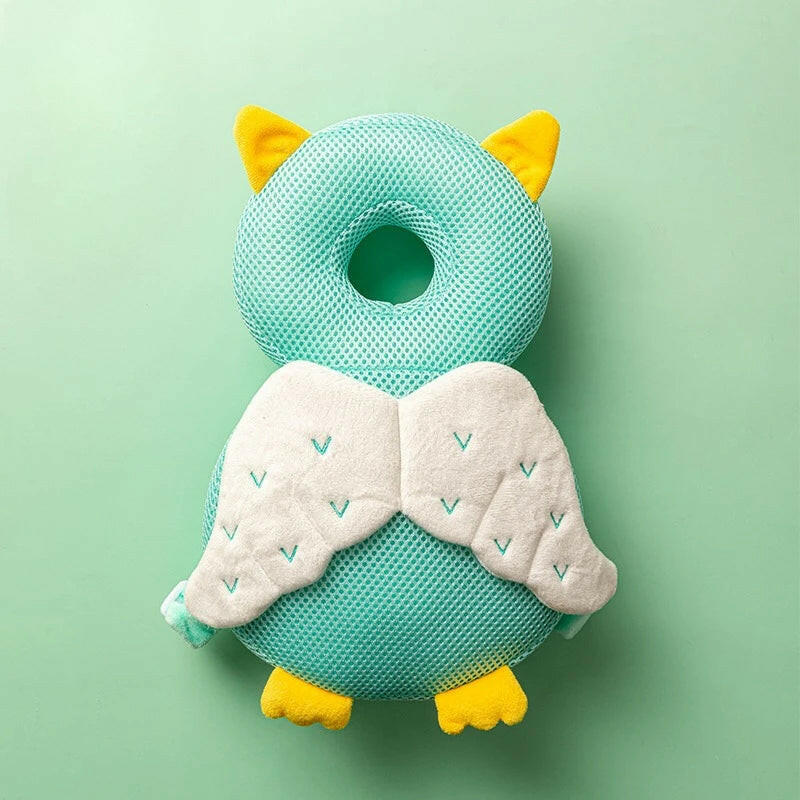 Teal owl-shaped pillow with yellow accents on a light green background