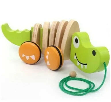Wooden toy caterpillar with green body, orange wheels, and a green pull string on a white background